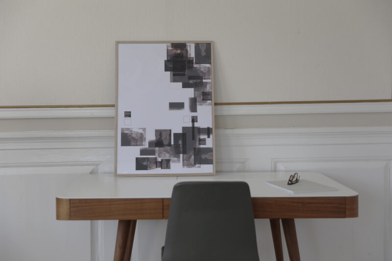 a work table with a thin oak frame standing on it with an art print inside with the title Selected Blacks 06
