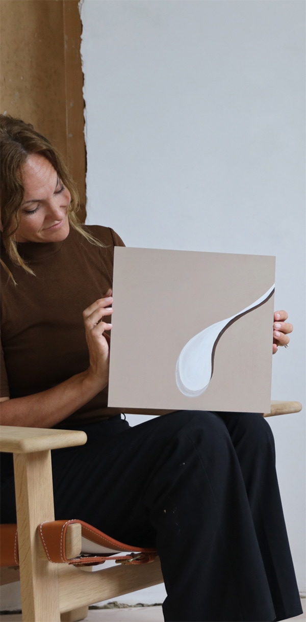 woman sitting in a chair is holding original artwork in her hands