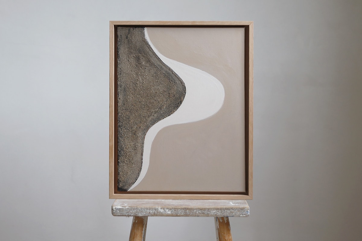 Flow 01 mixed media. artwork in beige, brown and white hues in an oak frame, placed on a stool